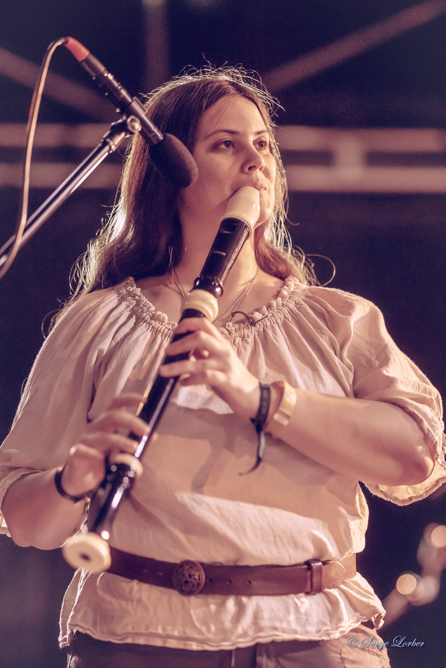 Musicienne jouant de la flûte à bec ténor devant un micro